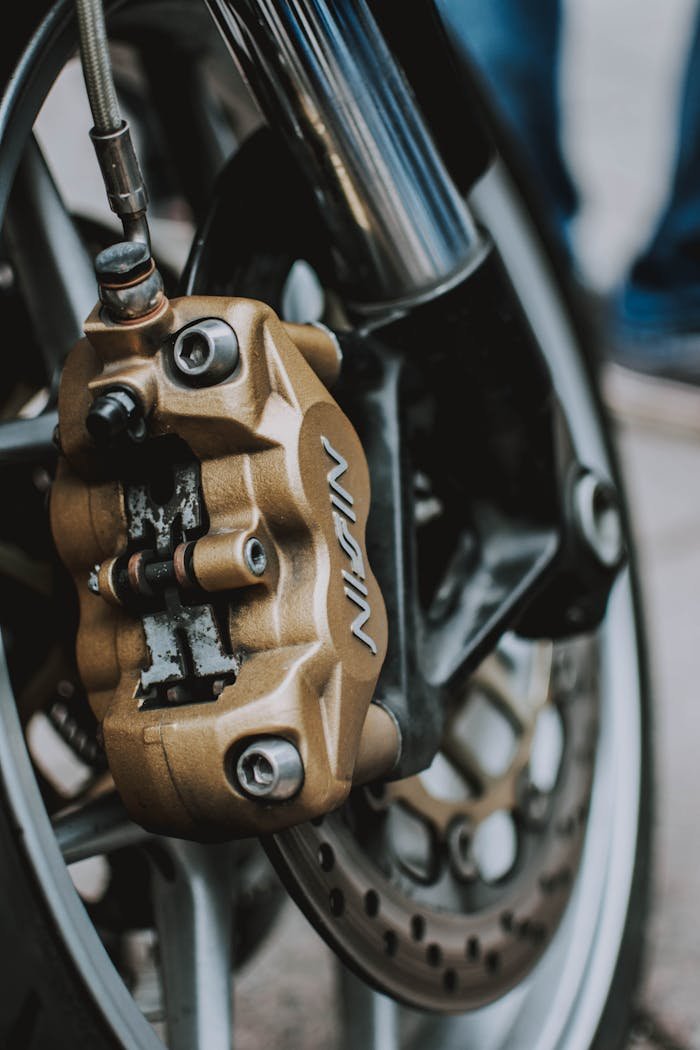 Detailed close-up of a motorcycle brake caliper and wheel showcasing engineering precision.